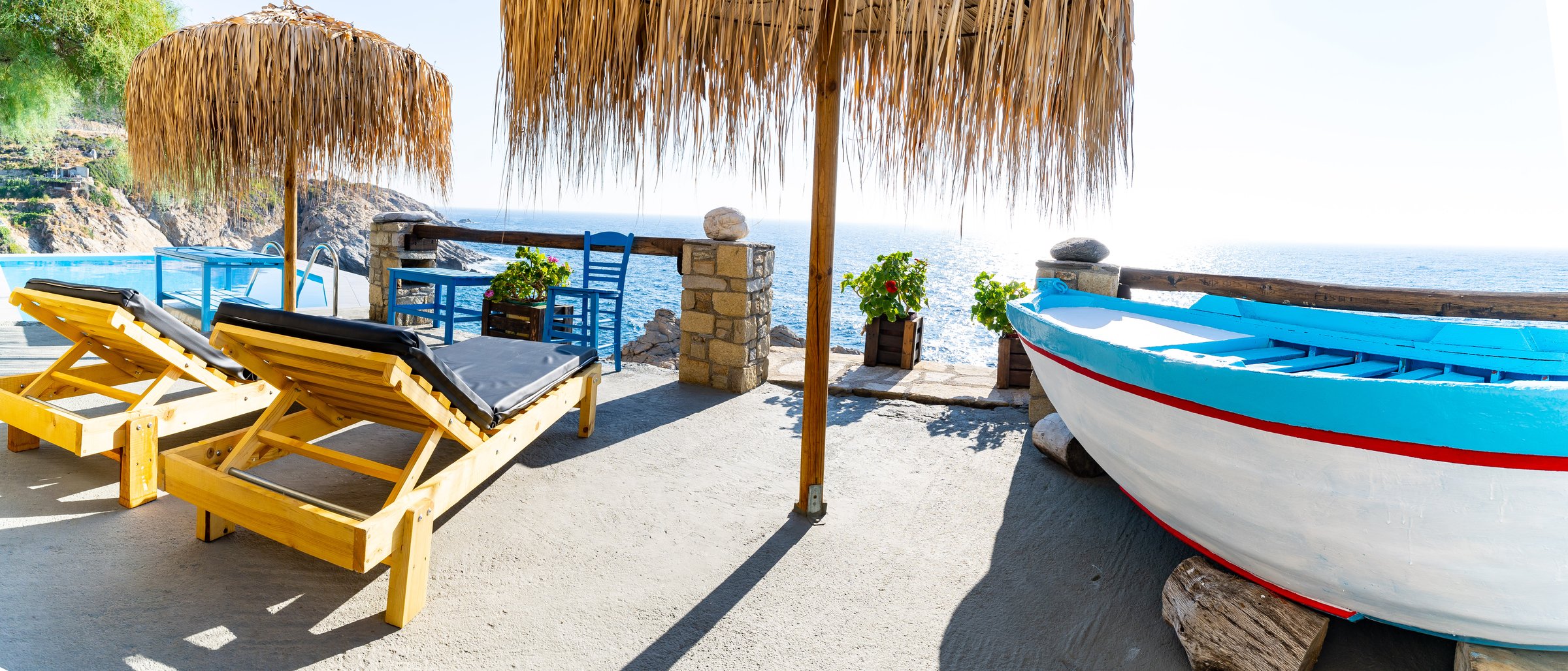 Outdoor sun lounge with sea view and traditional fishing boat